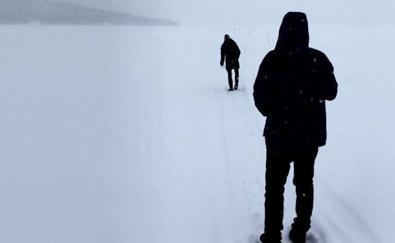 two figures in the snow walking away