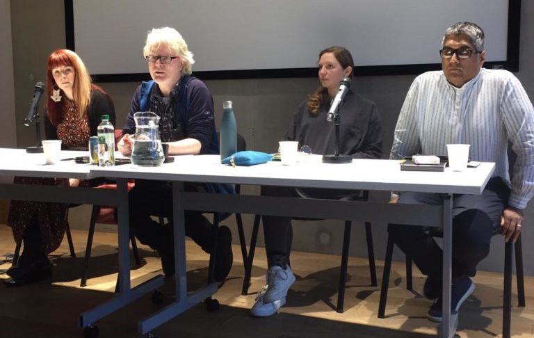 A panel of 2 men and 2 women behind a table