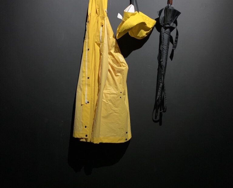 Yellow sou’ester and hat with umbrella hanging on coat hook.
