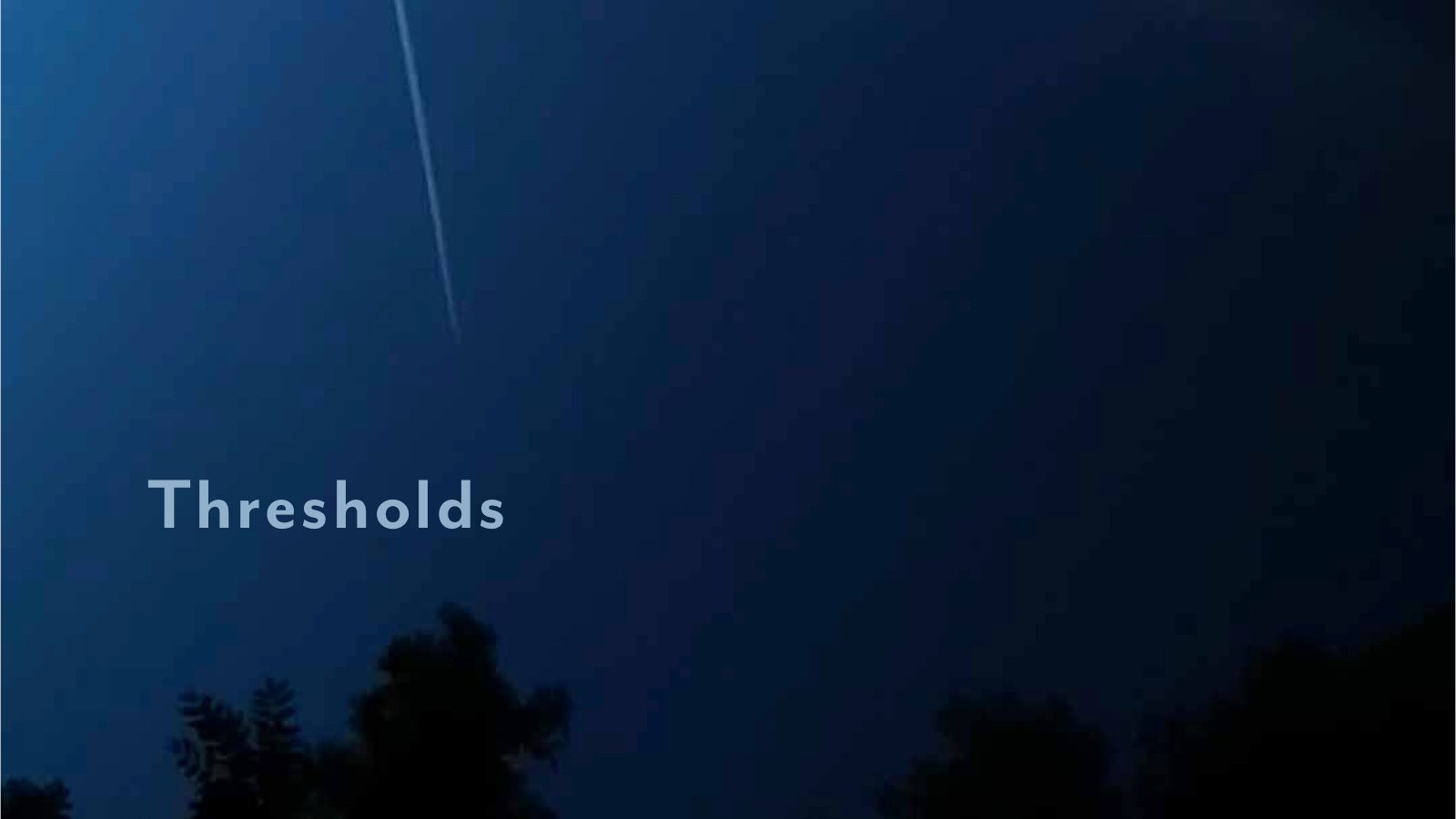 A blue black night sky wiyth contrail
